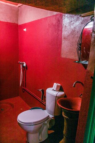 a red bathroom with a toilet and a sink at Kasbah Maison D’hôte Lalla Zahra in Aït Baha