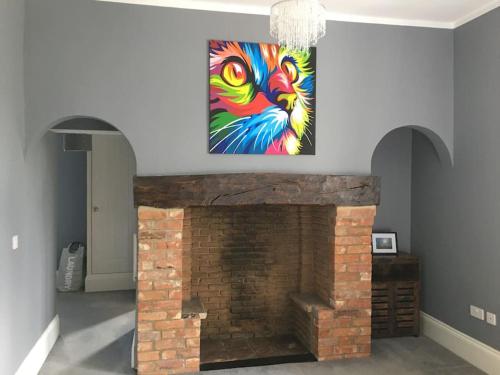 a painting of a peacock is hanging over a fireplace at Stylish 2 Bed Apart In The Heart of North Norfolk in North Walsham