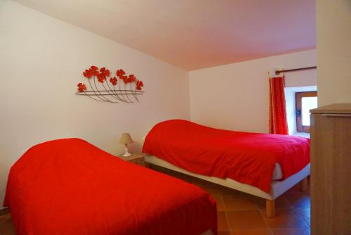 two beds in a room with red sheets at Maison de 2 chambres avec piscine partagee sauna et jardin amenage a Simiane la Rotonde in Simiane-la-Rotonde