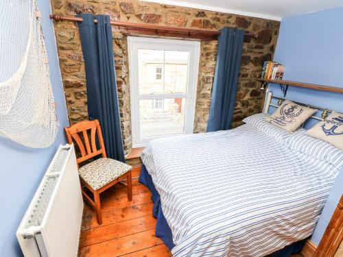 a bedroom with a bed and a chair and a window at Rock House in Haverfordwest