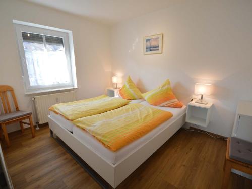 una camera da letto con un letto con due lampade e una finestra di Ferienwohnungen Seeburger Weg a Carolinensiel