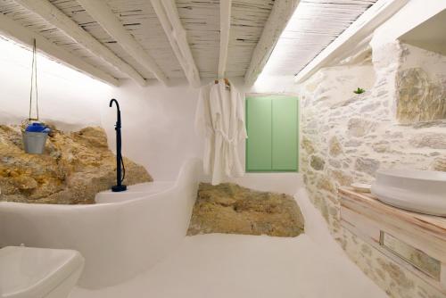 a bathroom with white walls and a stone wall at Blue Vorna in Ano Syros