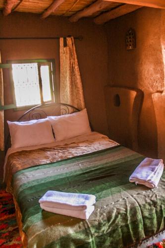 a bedroom with a bed with two towels on it at Kasbah Maison D’hôte Lalla Zahra in Aït Baha