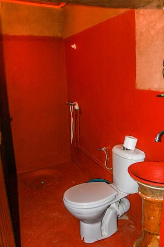 a red bathroom with a toilet and a sink at Kasbah Maison D’hôte Lalla Zahra in Aït Baha