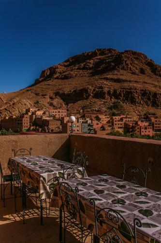 two tables and chairs with a mountain in the background at Kasbah Maison D’hôte Lalla Zahra in Aït Baha