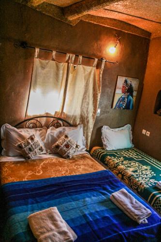 a bedroom with two beds and a window at Kasbah Maison D’hôte Lalla Zahra in Aït Baha