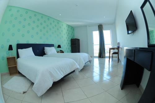 sypialnia z białym łóżkiem i telewizorem w obiekcie Free Zone Hotel w mieście Gzennaïa