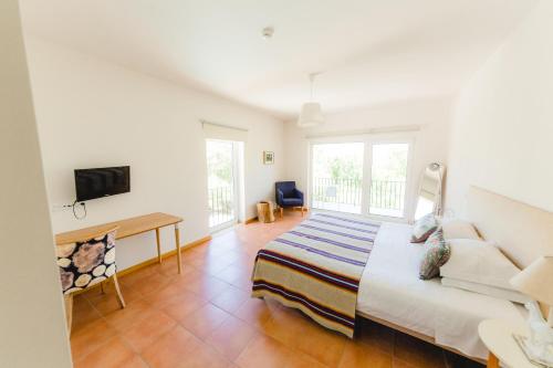 a bedroom with a bed and a couch and a tv at Retiro do Bosque Country House in Minde