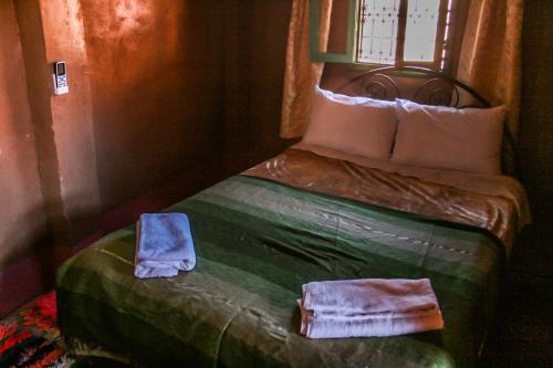 a bedroom with a bed with a green comforter at Kasbah Maison D’hôte Lalla Zahra in Aït Baha