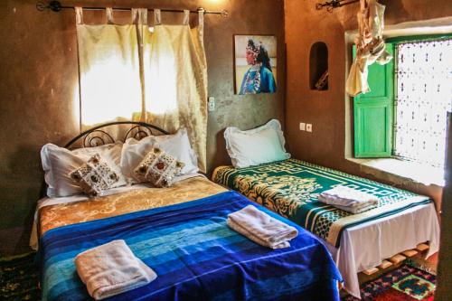 a bedroom with two beds and a window at Kasbah Maison D’hôte Lalla Zahra in Aït Baha