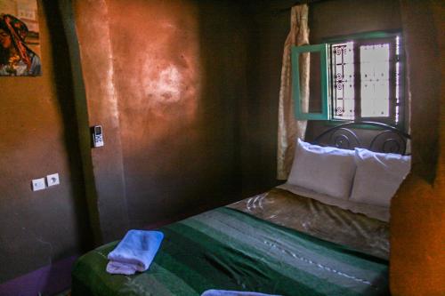 a small bedroom with a bed with a window at Kasbah Maison D’hôte Lalla Zahra in Aït Baha