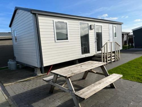 Une petite maison avec une table de pique-nique et un banc dans l'établissement Luxe stacaravan, à Middelkerke