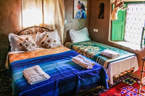 a bedroom with two beds and a window at Kasbah Maison D’hôte Lalla Zahra in Aït Baha