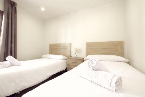 two twin beds in a room with white walls at Puerta de la Catedral in Toledo