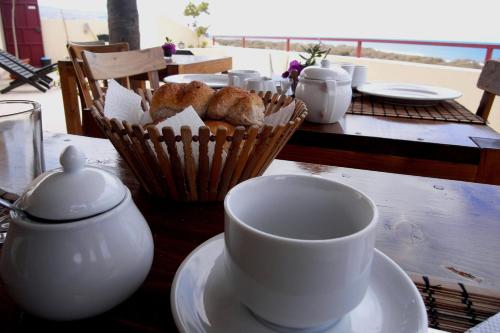 a table with cups and a basket of pastries on it at Casa Strela B&B Tarrafal in Tarrafal