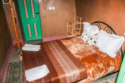 a bedroom with a bed and a green door at Kasbah Maison D’hôte Lalla Zahra in Aït Baha