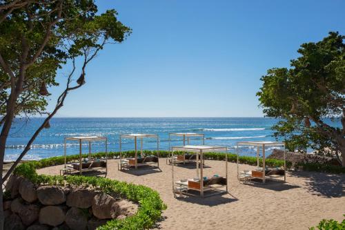 a beach with chairs and tables and the ocean at Dreams Bahia Mita Surf and Spa - All Inclusive in Punta Mita