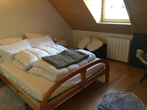 un letto con lenzuola bianche e un mucchio di coperte di Chalet tout confort 3 chambres a Cauterets