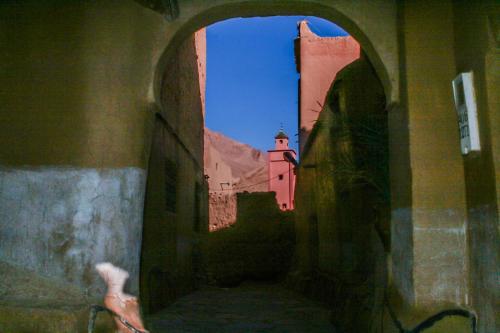 an archway in a building with a clock tower in the background at Kasbah Maison D’hôte Lalla Zahra in Aït Baha