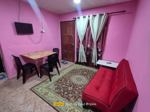 uma sala de estar com um sofá vermelho e uma mesa em Pink Homestay D'Perlis em Kangar