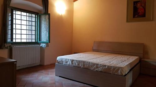 um quarto com uma cama e uma janela em Appartamento i Cipressi em Figline Valdarno