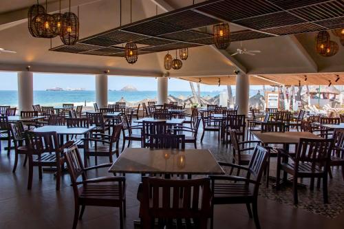 un restaurante con mesas y sillas y el océano en Emporio Ixtapa - with Optional All Inclusive en Ixtapa