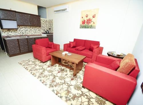 a living room with two red chairs and a table at زيفل للشقق المخدومة in Buraydah