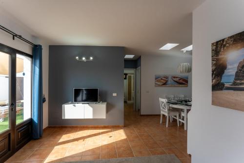 a living room with a table and a tv on a wall at villa del mar puerto del carmen in Puerto del Carmen