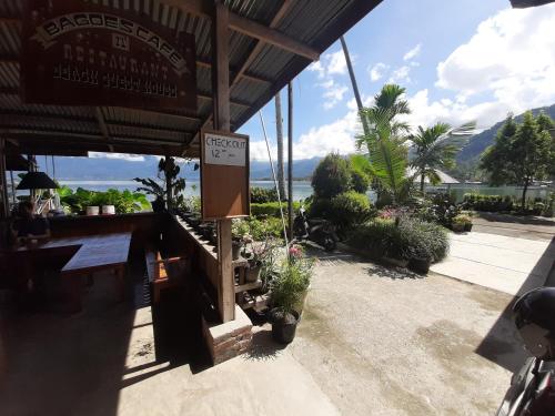 a restaurant with a sign on the front of it with plants at Beach Guest House in Maninjau
