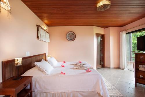a bedroom with a large white bed with red flowers on it at Pousada Mangabeiras in Ilha de Boipeba