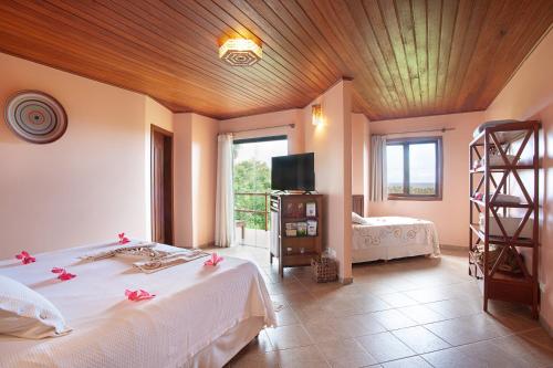 a bedroom with a bed and a television in a room at Pousada Mangabeiras in Ilha de Boipeba