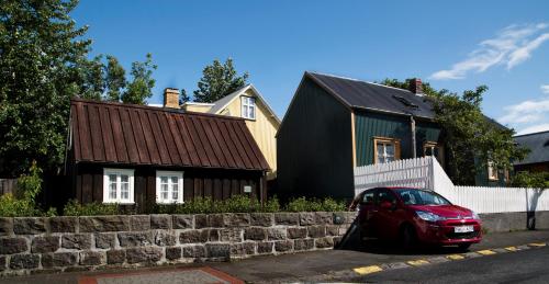 una macchina rossa parcheggiata di fronte a una casa di Vaktahouse a Reykjavik