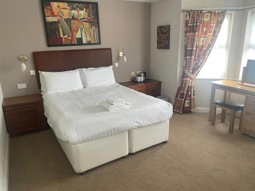 um quarto com uma cama branca, uma secretária e uma janela. em The Moorings Hotel em Edmondsley