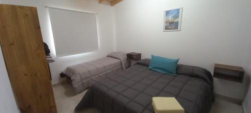 Dormitorio pequeño con cama y almohada azul en Departamentos x dia Viedma 2 CON COCHERA en Viedma
