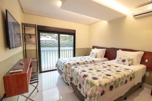 a bedroom with two beds and a balcony at Pousada Flores do Carmo in Pirenópolis