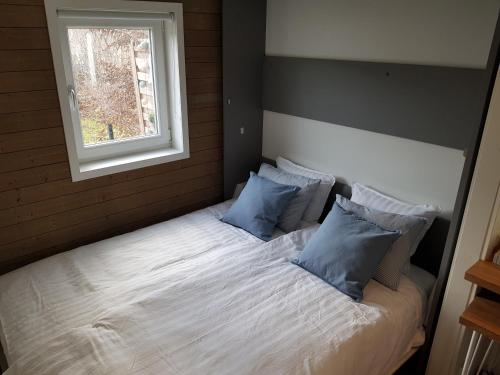 1 dormitorio con 1 cama con 2 almohadas y ventana en Lillhuset nära Stockholm en Tungelsta