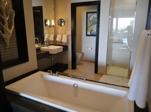 a bathroom with a large white tub and a sink at Zimbali 2007 in Ballito