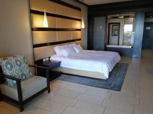 a bedroom with a large bed and a chair at Zimbali 2007 in Ballito