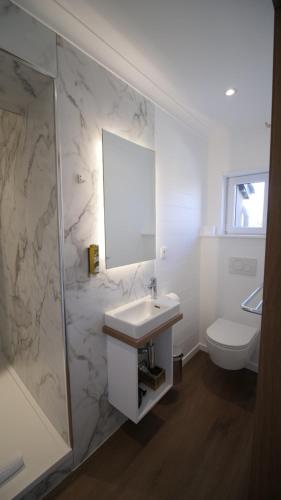 a white bathroom with a sink and a toilet at Auberge la Hutte Lurette in Paliseul