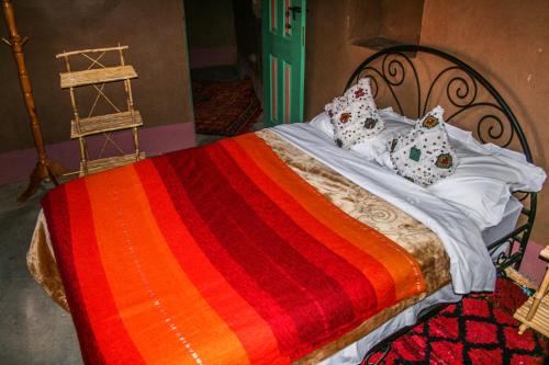 a bed with a colorful blanket and pillows on it at Kasbah Maison D’hôte Lalla Zahra in Aït Baha