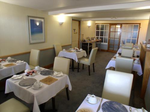 une salle à manger avec des tables et des chaises blanches dans l'établissement St Magloire, à Saint Aubin