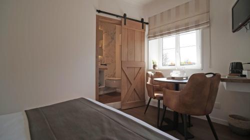 a bedroom with a bed and a table and chairs at Auberge la Hutte Lurette in Paliseul