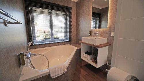 a bathroom with a bath tub and a sink at Auberge la Hutte Lurette in Paliseul