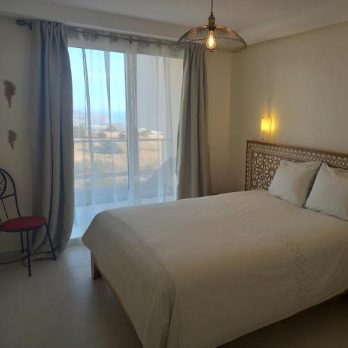 um quarto com uma cama e uma grande janela em Taghazout Océan with pool , fitness and ocean view em Taghazout