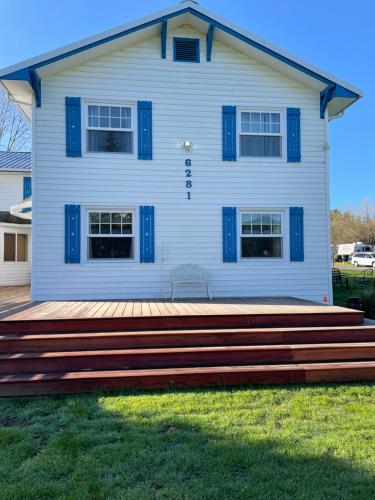 a white house with blue shutters and a wooden deck at Foster Lake Inn in Sweet Home