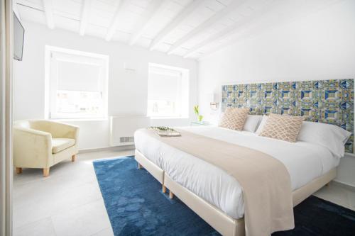 a white bedroom with a large bed and a chair at Casa Platón Páramo in Oropesa