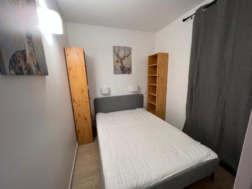 ein kleines Schlafzimmer mit einem Bett und einem Regal in der Unterkunft Bel Appartement en rez de chaussée in Cauterets