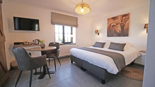 a bedroom with a bed and a table and a tv at Auberge la Hutte Lurette in Paliseul