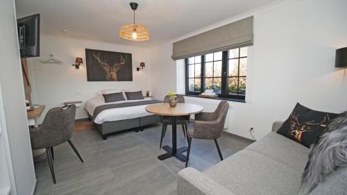 a bedroom with a bed and a table and a couch at Auberge la Hutte Lurette in Paliseul
