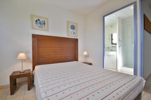 1 dormitorio con 1 cama grande y espejo grande en Appartement dans résidence avec piscine et parking en Uzès